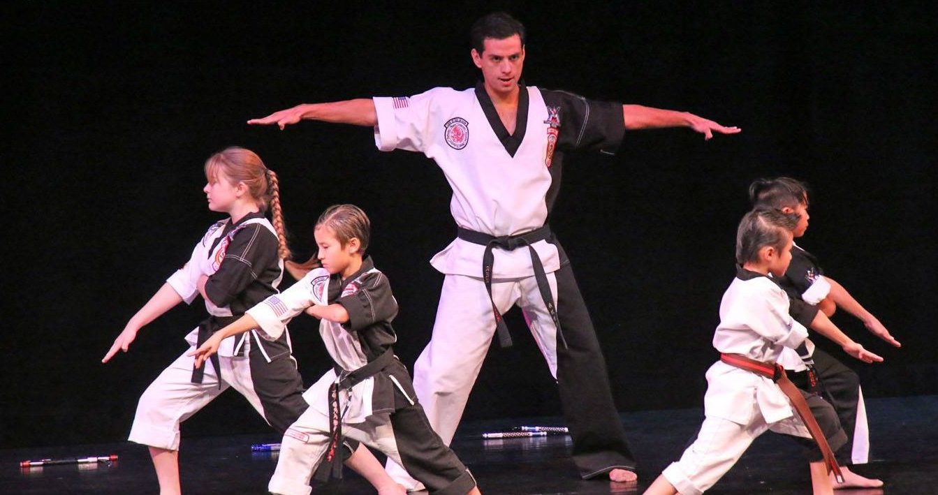 A Red Dragon instructor leading students through a kata on stage
